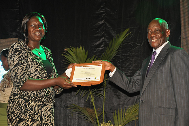 Helen Lubowa Executive Director of UCOTA receiving a certificate of recognition for Women in Conservation Leadership from UWA Board of Trustees Chairman