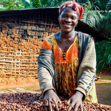 Photograph of woman cocoa farmer smiling and digging into her sustainable cocoa bean crop