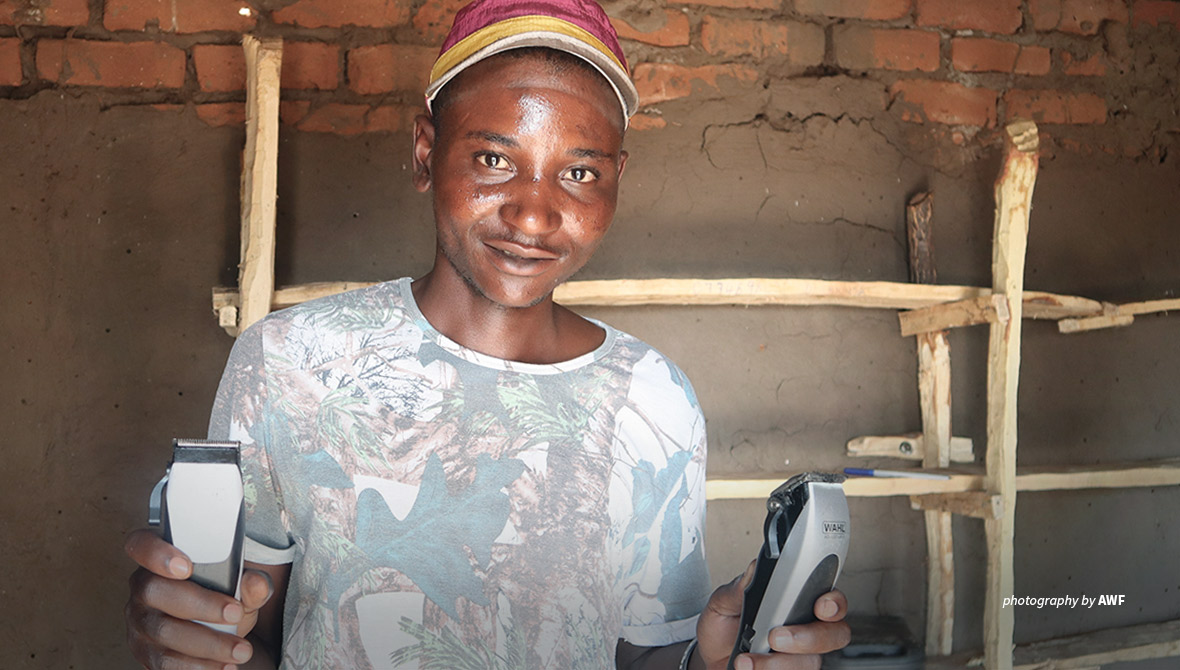 Portrait of wildlife scout Desire Chisunga holding hairdressing equipment