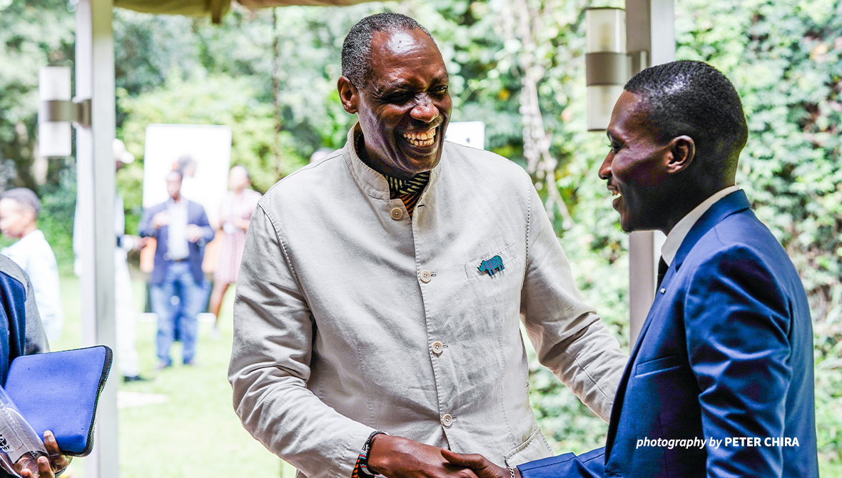 AWF's CEO Kaddu Sebunya shaking hands with a young person. 