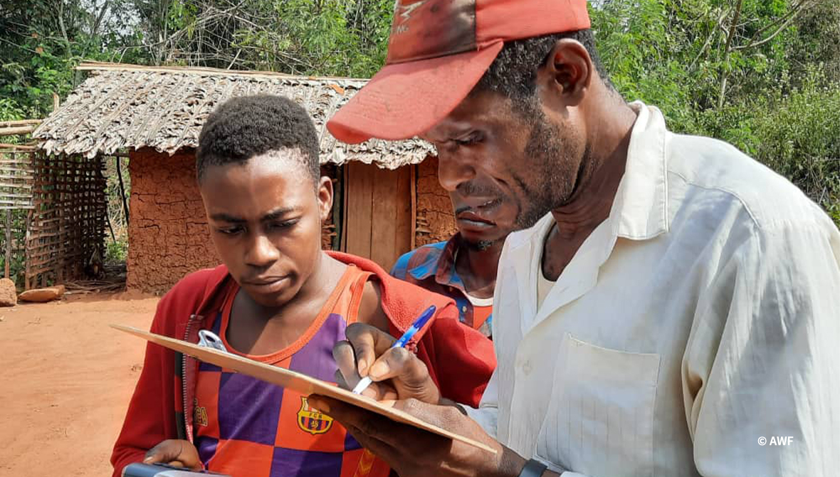 Two people look at a clipboard.