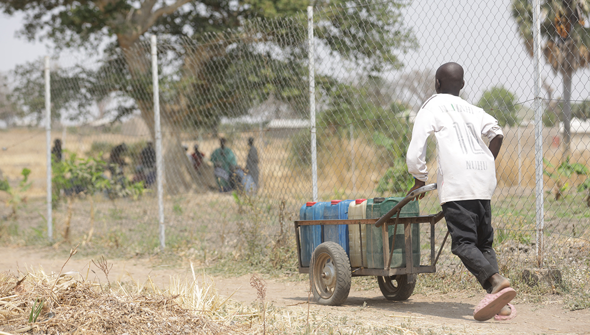 Young boy pushing a barrel of water from the Rural Resource Center in Tchamba