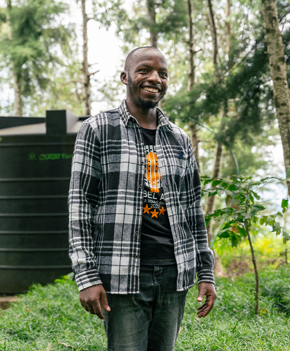 A young person smiles among greenery.