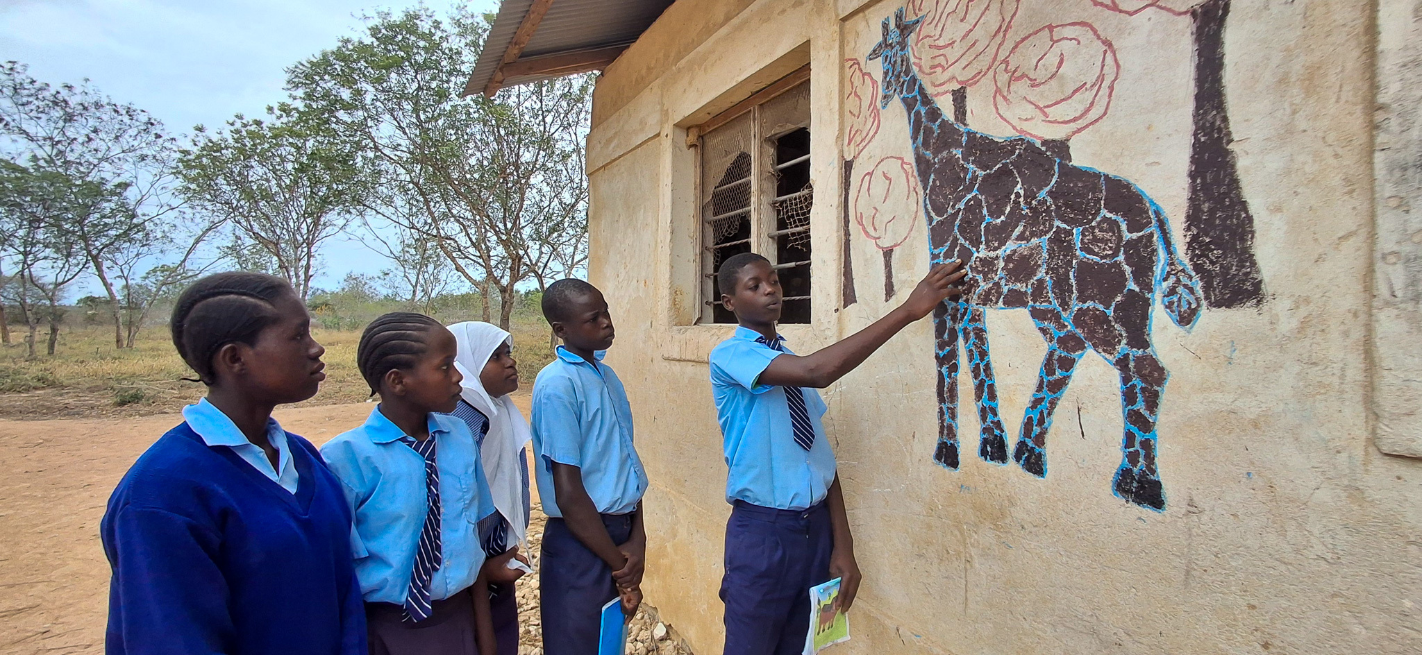 Bakari showing his classmates some of his artwork