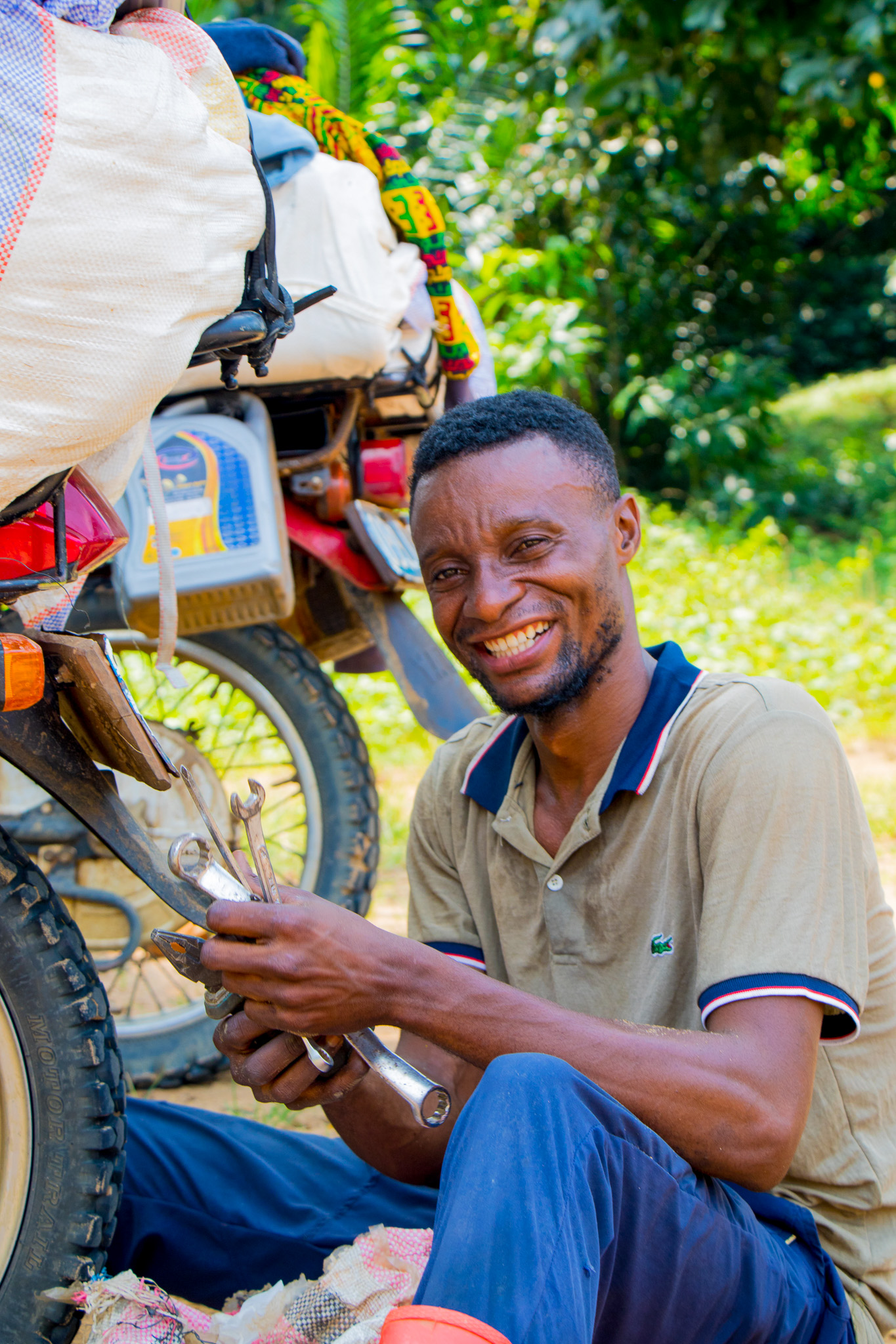 Jeancy Luaka jouyously prepares his motor cycle for another trip through the dense forest. 