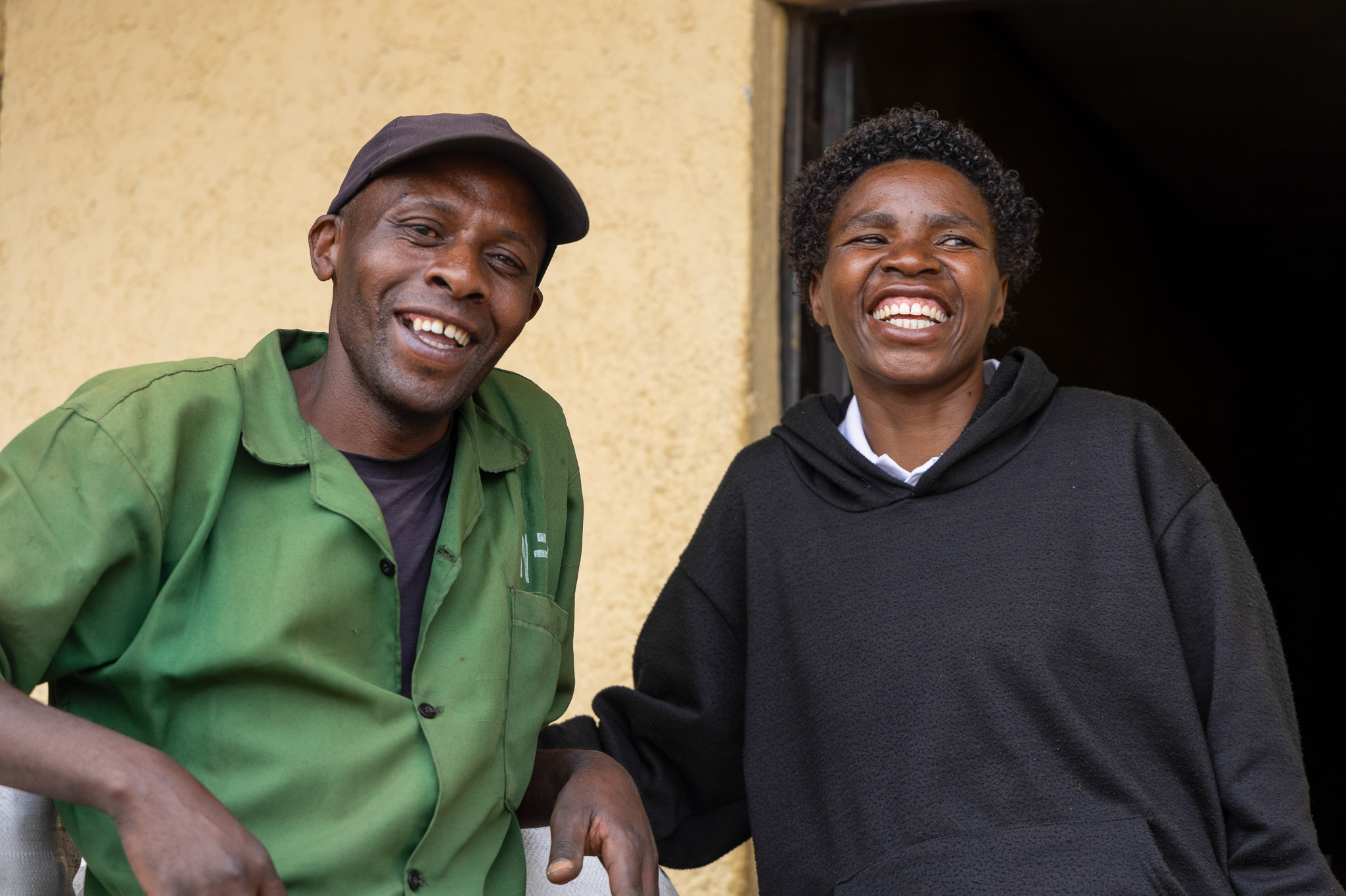 Mukarwego Agnes with a community member outside her home in the Volcanoes landscape