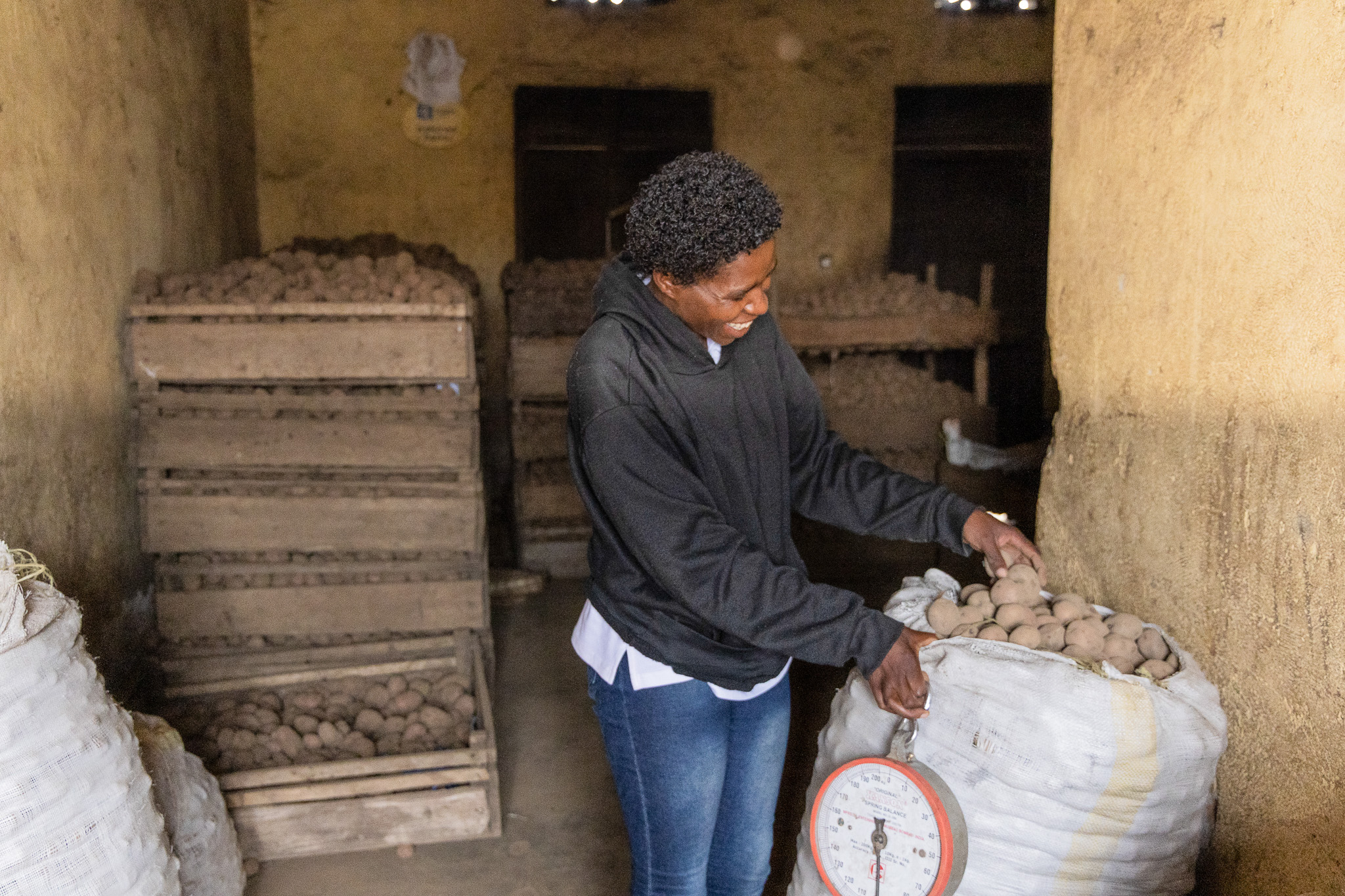 Agnes weighs sacks of Irish potatoes in her storage space