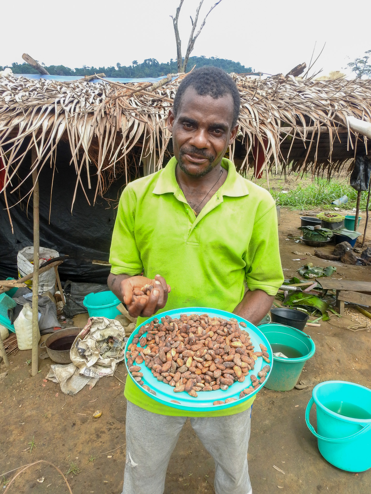Jean Daniel stands infront of his home holding cocoa seeds which he was able to harvest from his cocoa farm for the first time. 