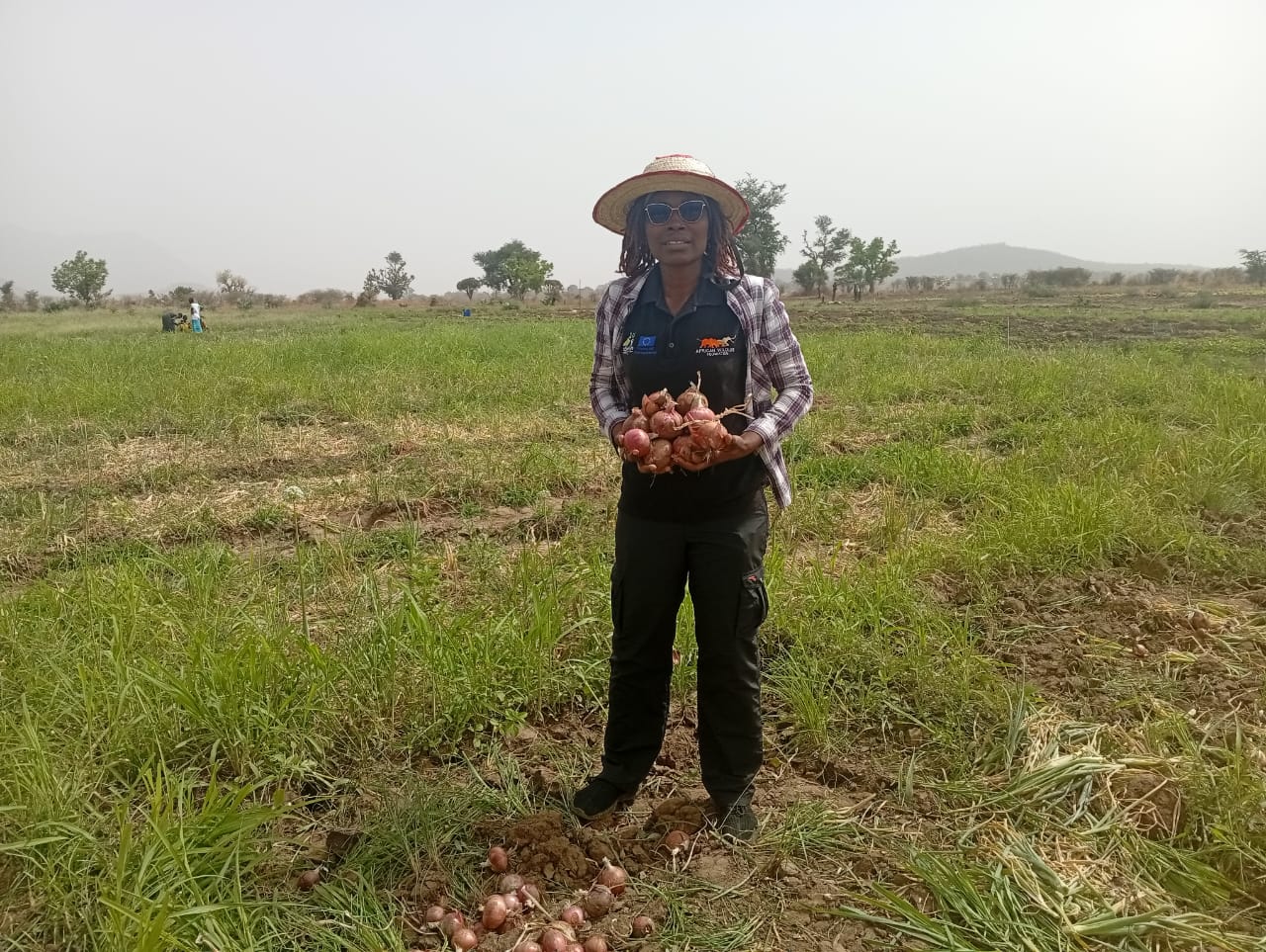 AWF Community Development Assistant Blandine Moueni with the onion harvest of the community farm.