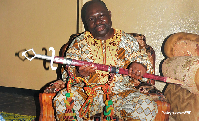 AWF Cameroon Country Coordinator Manfred Aimé Epanda is recognized by the Tchamba chiefdom for his contribution to local development Photo of AWF Cameroon Country Coordinator holding ceremonial sword on receiving warrior title in Tchamaba chiefdom