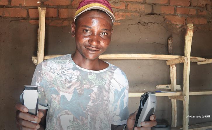 Portrait of wildlife scout Desire Chisunga holding hairdressing equipment