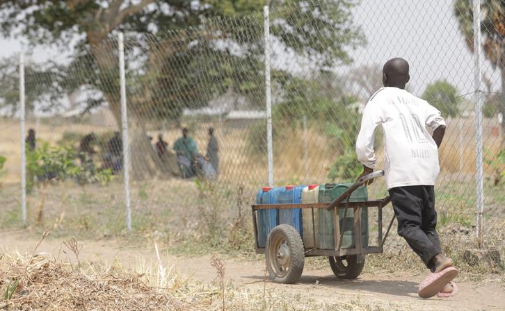 Young boy pushing a barrel of water from the Rural Resource Center in Tchamba