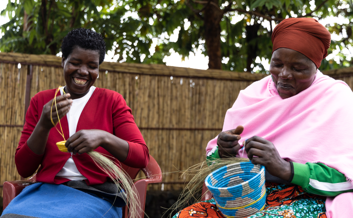 Mukamakuza Esther (right) skillfully weaving a basket at the Community-Based Tourism Center in Kinigi, Musanze District, with her colleague.