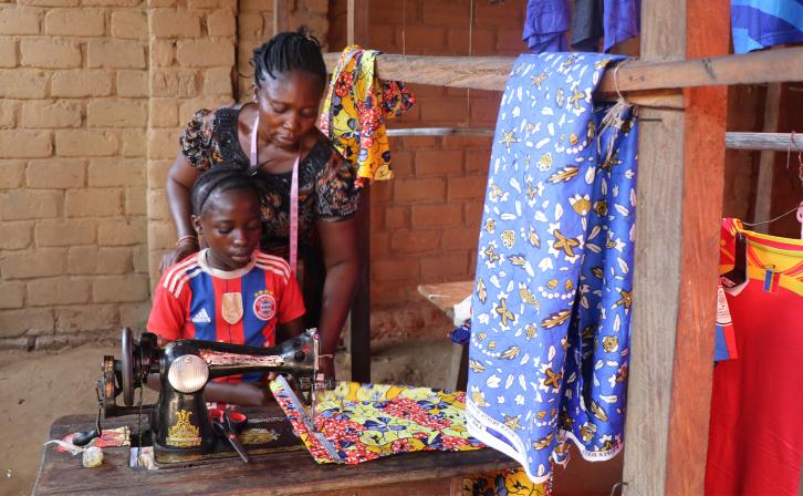 Louise Wanga Boondo assists her mother with a client’s order, learning each stitch under her attentive gaze in their small workshop.