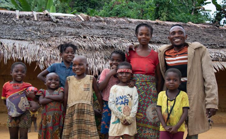 Nsembe Balombo Guy with his family and nephews in front of his home, a symbol of newfound stability and empowerment.