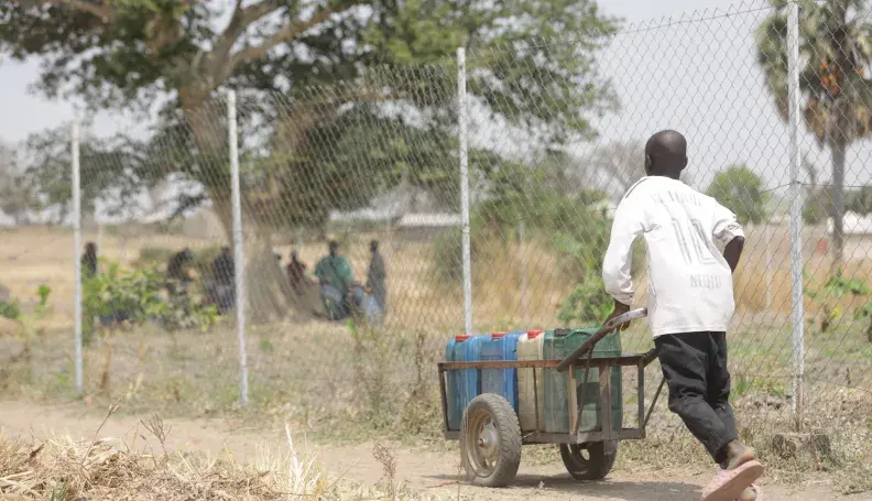 Young boy pushing a barrel of water  from the Rural resource Center in Tchamba