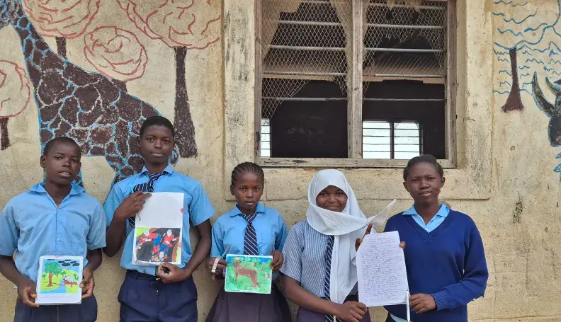 Bakari Ali Mangale and his classmates stand alongside his artwork 