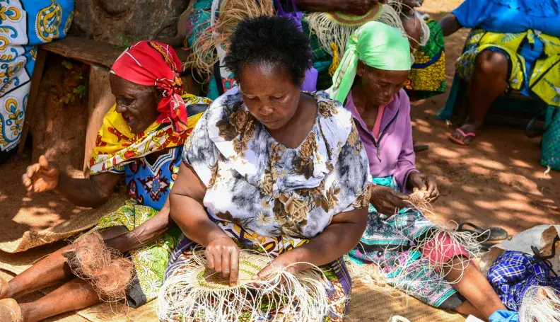 Local women in Taita Taveta County engaging in basket weaving at a communal meeting point.