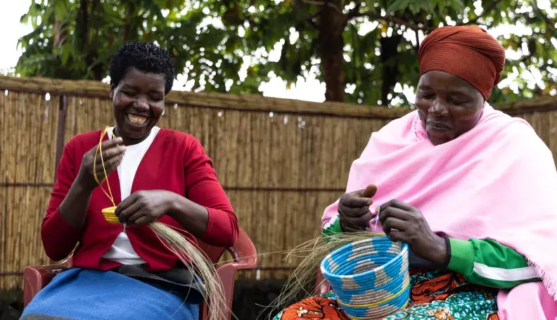Mukamakuza Esther (right) skillfully weaving a basket at the Community-Based Tourism Center in Kinigi, Musanze District, with her colleague.