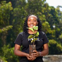 Photo of climate activist Elizabeth Wathuti holding a seedling