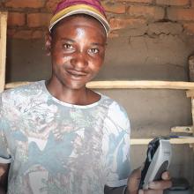 Portrait of wildlife scout Desire Chisunga holding hairdressing equipment