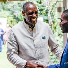 AWF's CEO Kaddu Sebunya shaking hands with a young person. 