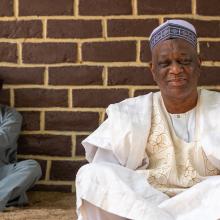 Medium shot of two men sitting in front of a brick wall.