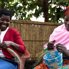 Mukamakuza Esther (right) skillfully weaving a basket at the Community-Based Tourism Center in Kinigi, Musanze District, with her colleague.