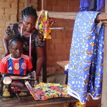 Louise Wanga Boondo assists her mother with a client’s order, learning each stitch under her attentive gaze in their small workshop.