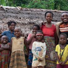Nsembe Balombo Guy with his family and nephews in front of his home, a symbol of newfound stability and empowerment.