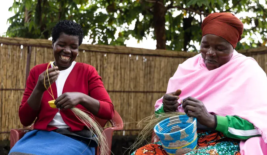 Mukamakuza Esther (right) skillfully weaving a basket at the Community-Based Tourism Center in Kinigi, Musanze District, with her colleague.