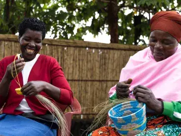 Mukamakuza Esther (right) skillfully weaving a basket at the Community-Based Tourism Center in Kinigi, Musanze District, with her colleague.