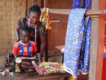 Louise Wanga Boondo assists her mother with a client’s order, learning each stitch under her attentive gaze in their small workshop.