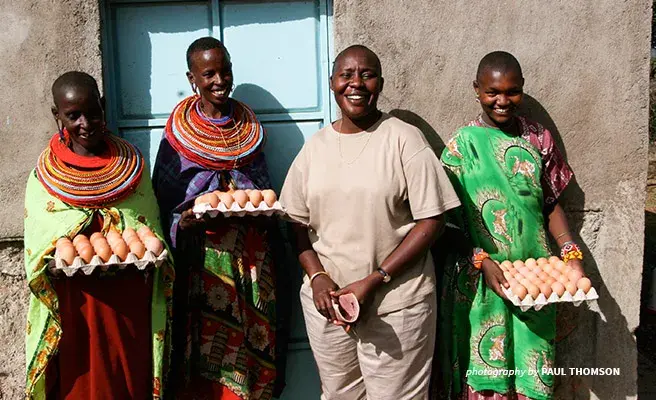 Fiesta Warinwa stands with women of Nkiloriti Group Ranch and their special kuku eggs. Image of Fiesta Warinwa, AWF Director of Policy Engagement