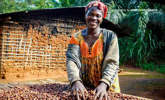 Photograph of woman cocoa farmer smiling and digging into her sustainable cocoa bean crop